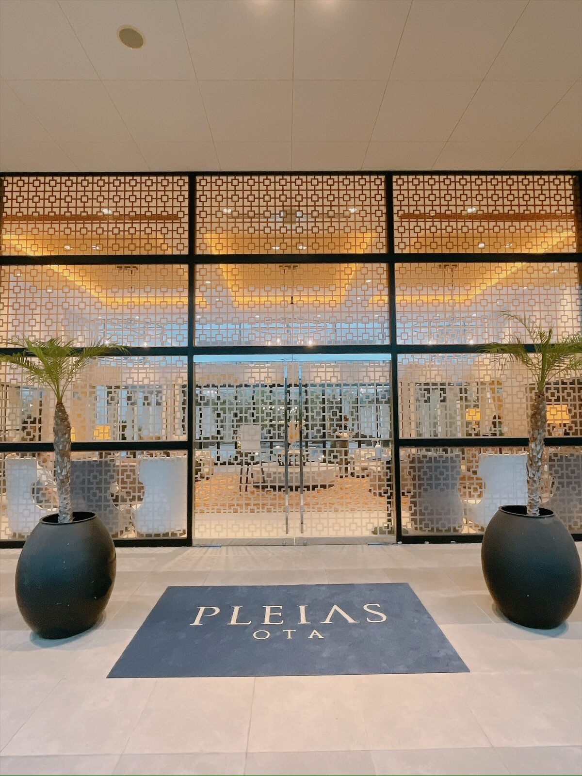 ガラス張りの入り口の前に、PLEIAS OTA と書かれたマットが敷かれている