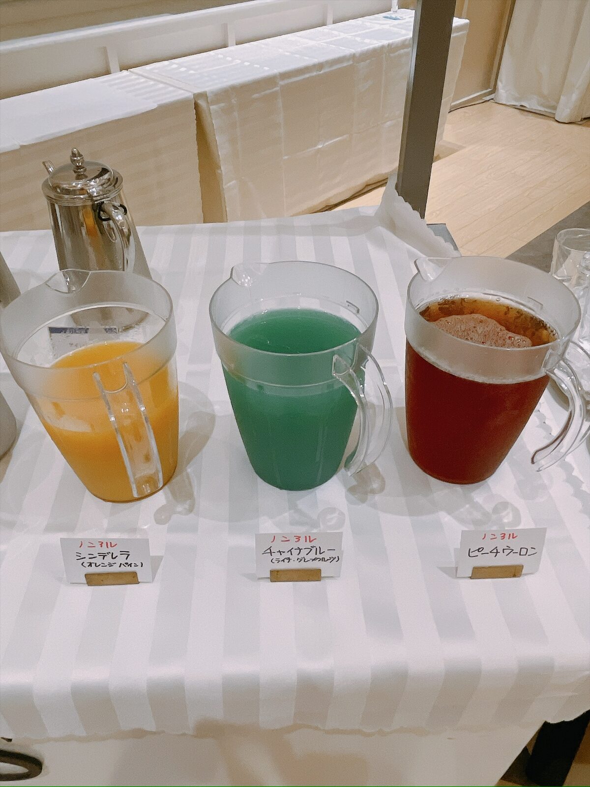 白いテーブルに、オレンジ・青・赤の3色の飲み物が入ったピッチャーが並んでいる