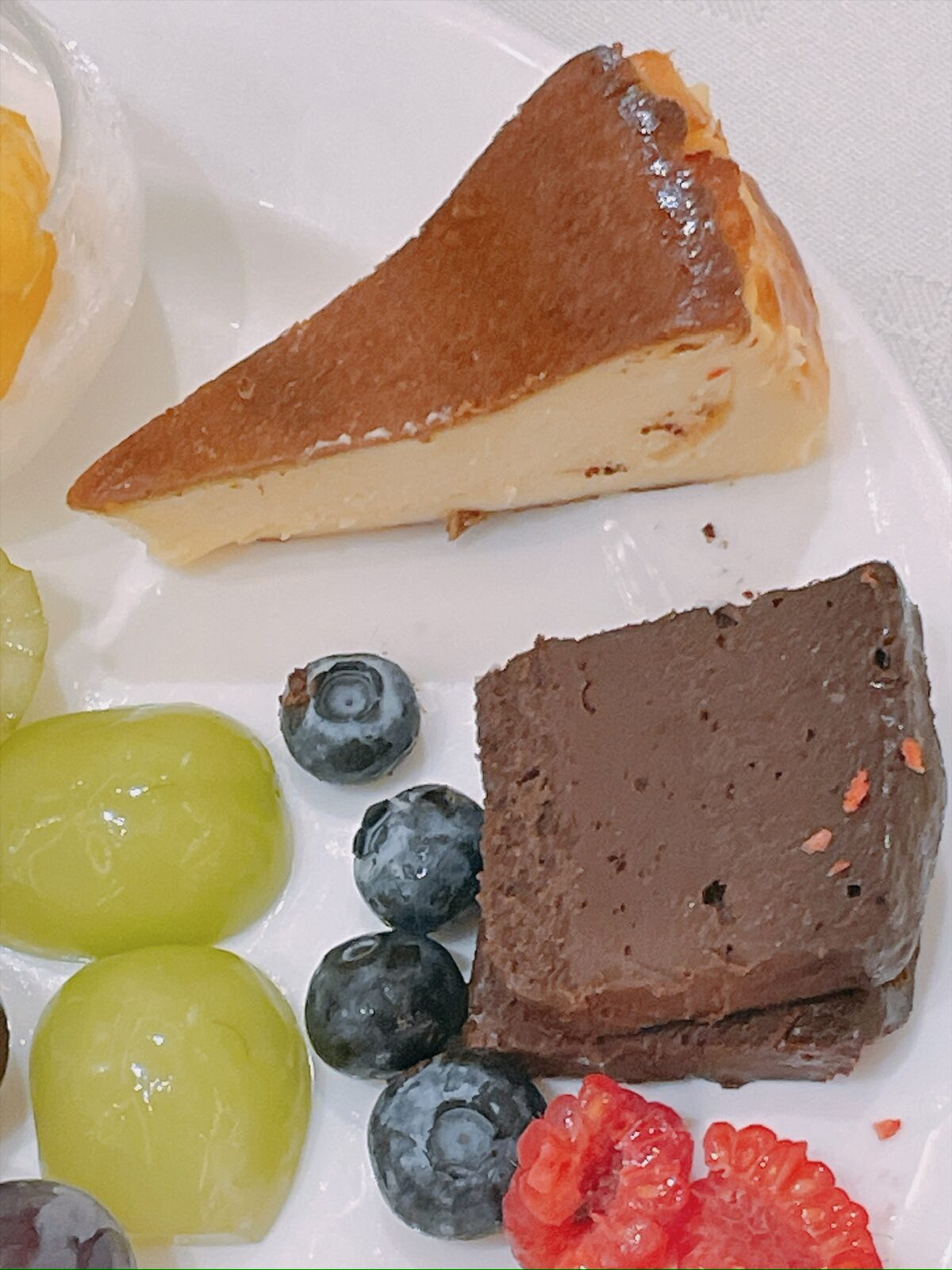 白い皿に、チーズケーキとガトーショコラ、ぶどうとブルーベリー