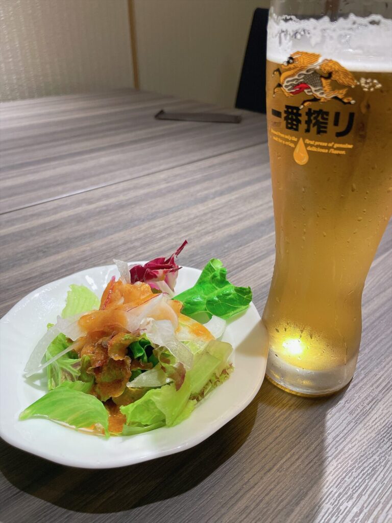 生ビールのグラスと、サラダを取り分けた皿