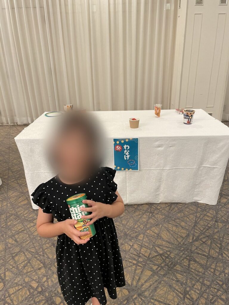 縁日の輪投げブースの前に立つ子ども
