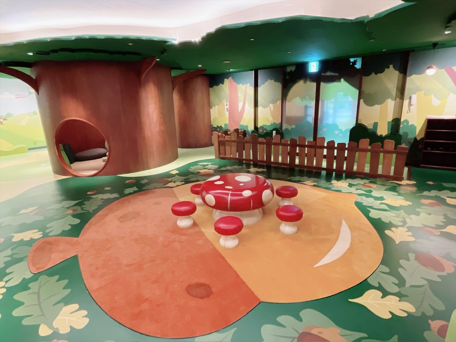 森をテーマにした部屋の中。手前の切り株の内側がベンチになっていて、中央に赤に白い水玉のきのこの形のテーブルと椅子が置かれている