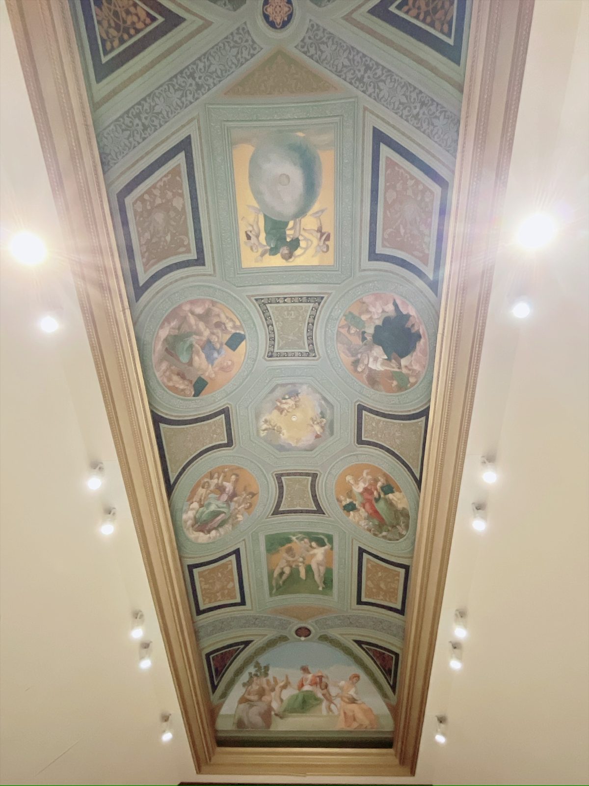 教会天井のフレスコ画。淡い青緑の地に円形や四角の枠取りがいくつも並び、天使や人物を描いた絵が収められている