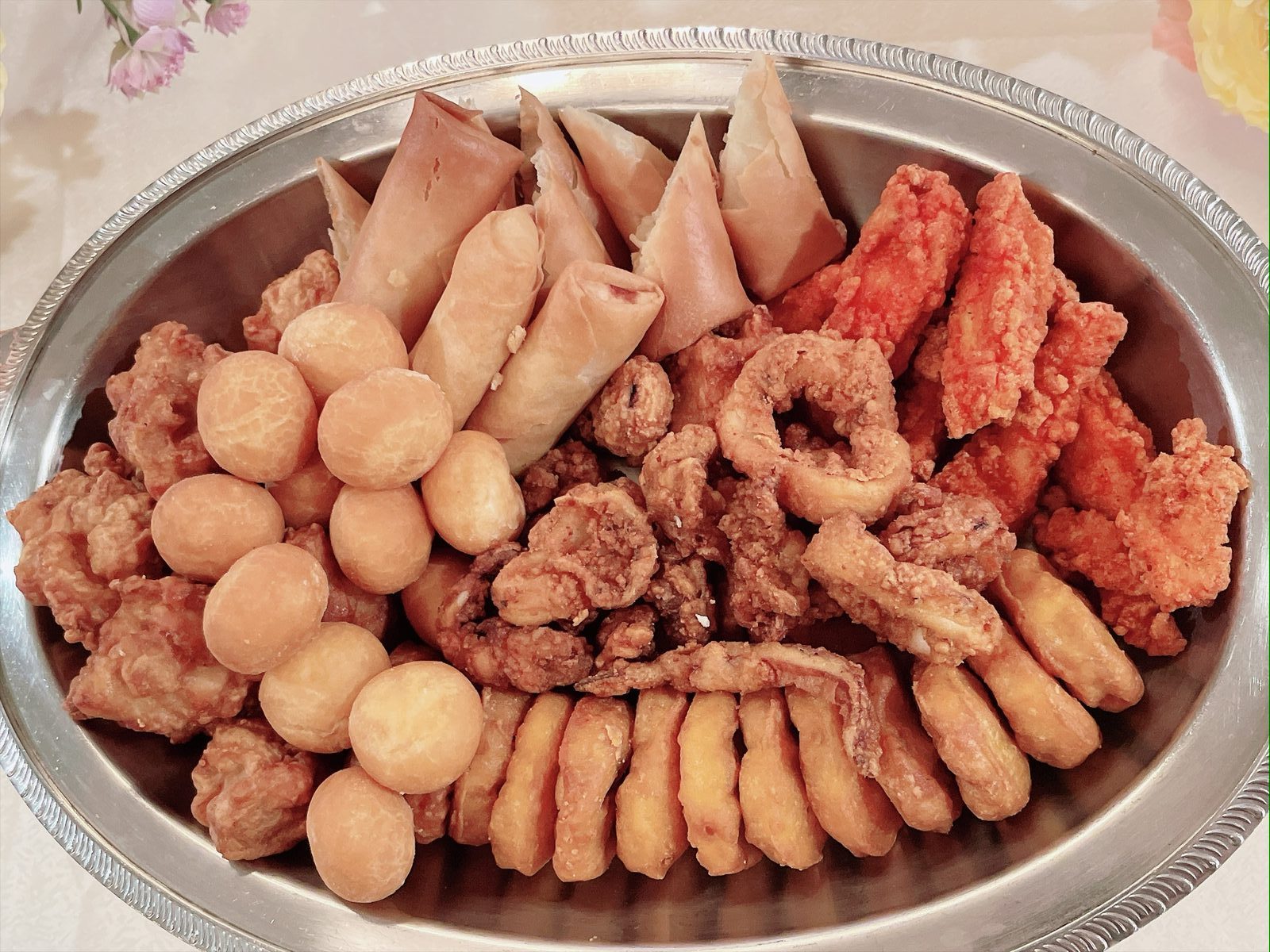 銀色の丸皿に、揚げた春巻きやチーズボール、唐揚げ、イカリング、エビフライなど様々なフライが盛り付けられている