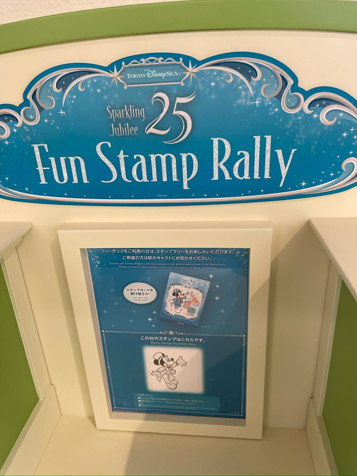 淡い青色の「Sparkling Jubilee 25 Fun Stamp Rally」の看板。その下に、スタンプの見本が入った案内が立てられている