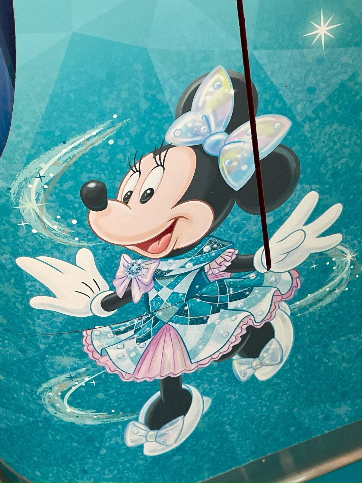 車内の壁に描かれた、水色の衣装をまとって踊るミニー。背景は青緑