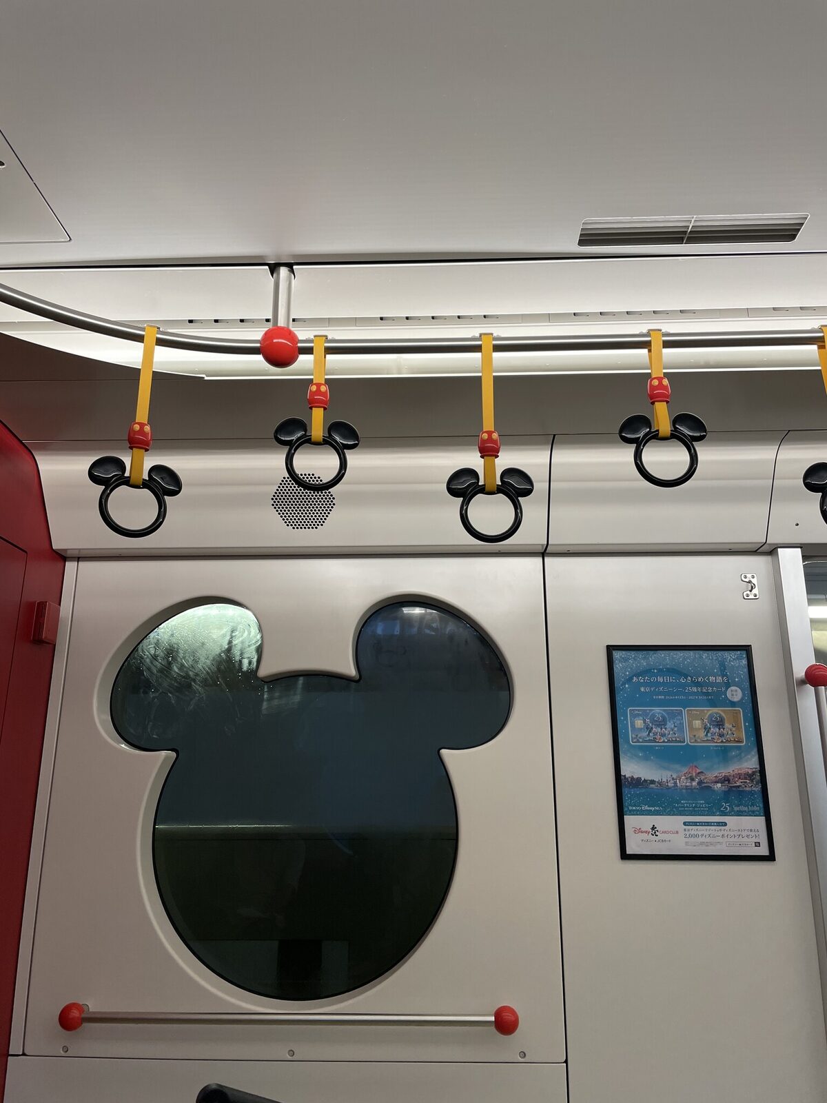 通常車両の車内。窓がミッキーの形にくり抜かれ、天井から下がる吊り革の輪もミッキーの形をしている