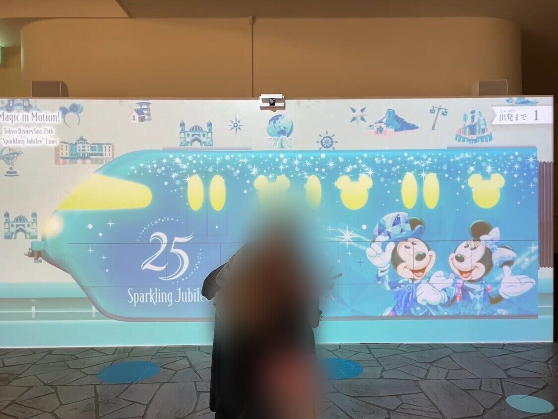 完成したスクリーン。水色のモノレールに「25 Sparkling Jubilee」の文字、ミッキーとミニーたちが描かれている。前に立つ人の姿はぼかしてある