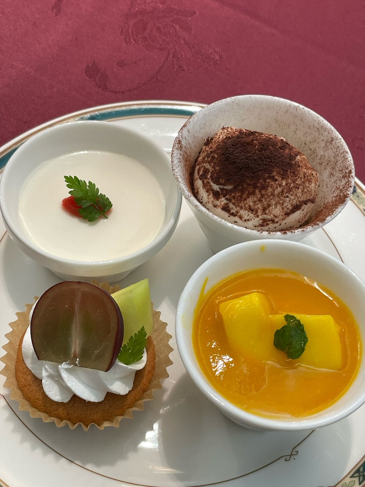1枚の皿に、杏仁豆腐、ティラミス、ぶどうとクリームのカップケーキ、マンゴープリン