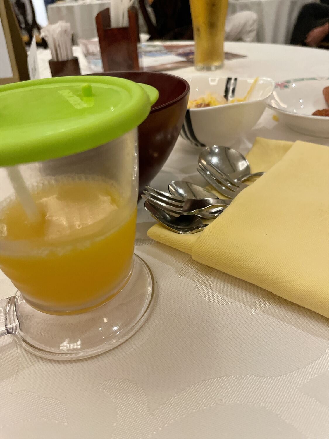 ふたとストローのついたカップに入ったオレンジ色の飲みもの