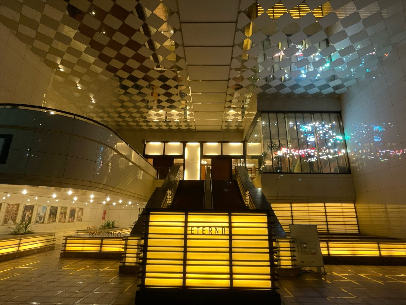 夜のエテルナ高崎のエントランス。階段の手前に「ETERNA」と入った光る看板、天井は市松模様の鏡張り